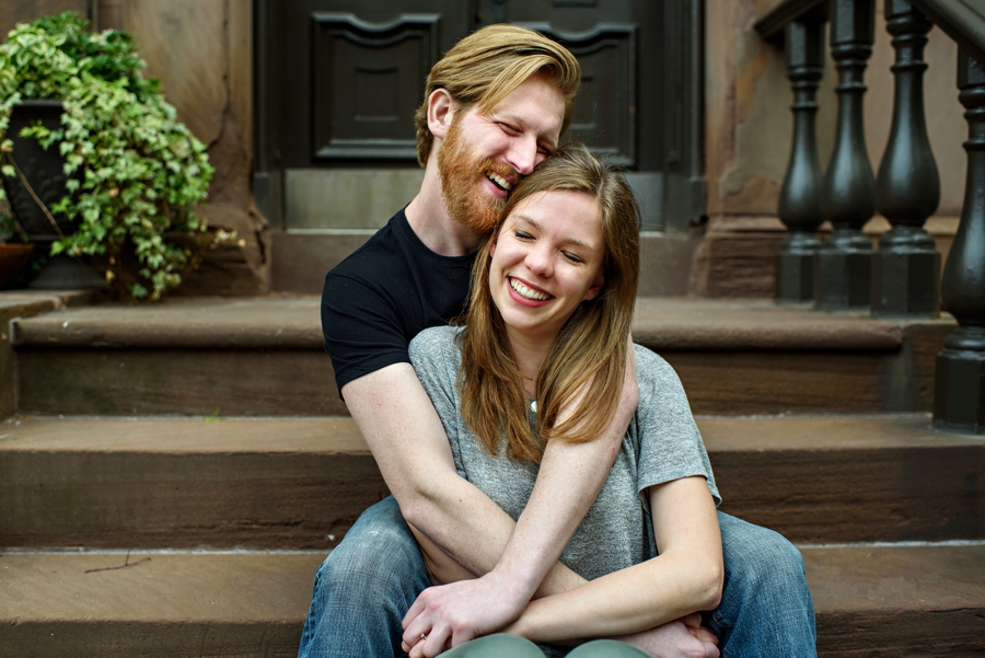 A couple in love sit on the steps of a center city apartment during engagement session.